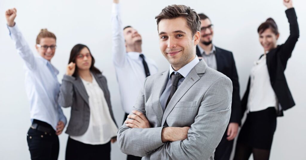 businessman in a suit standing in front of a cheering team